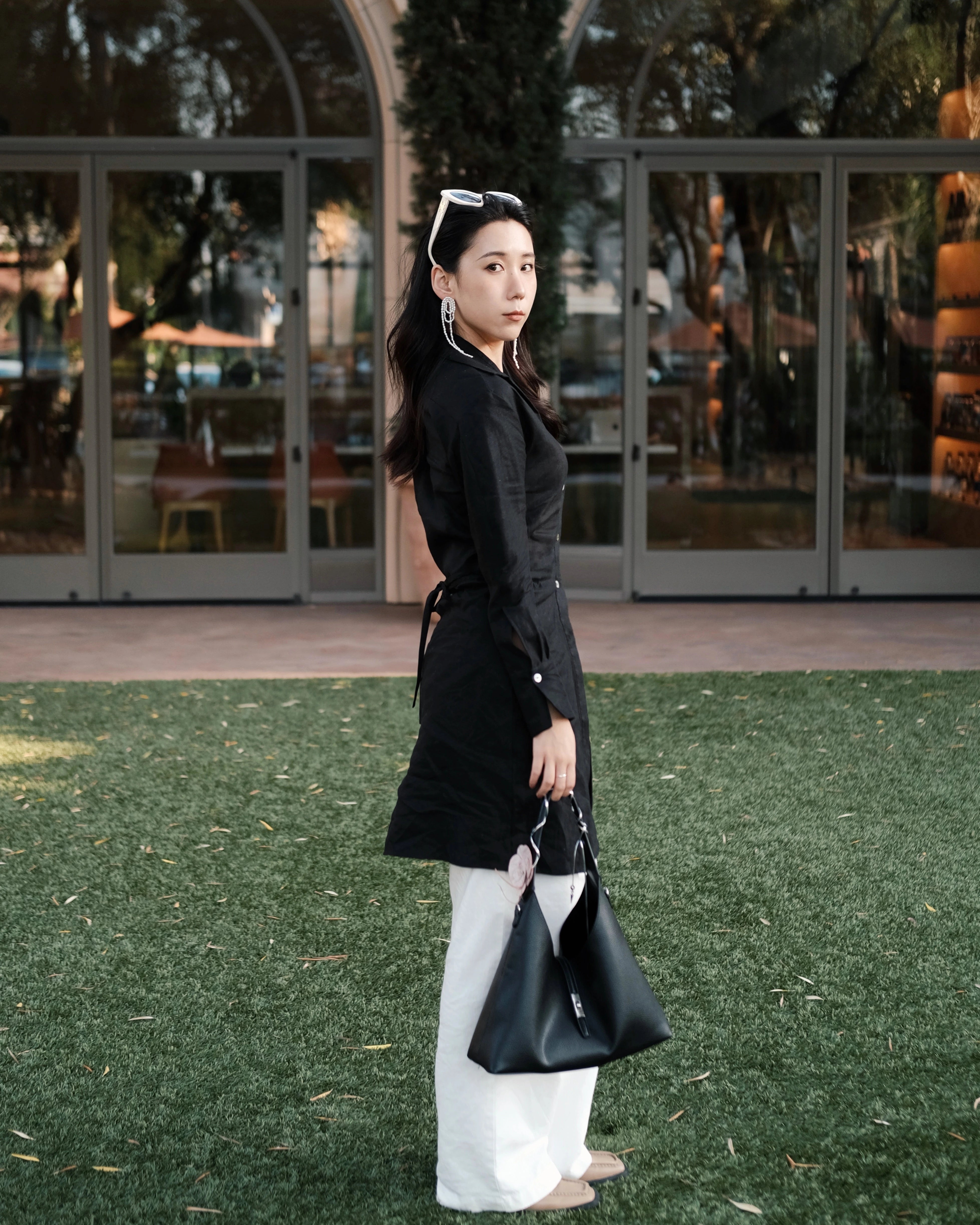 Girl holding a black tote bag standing in front of a glass door