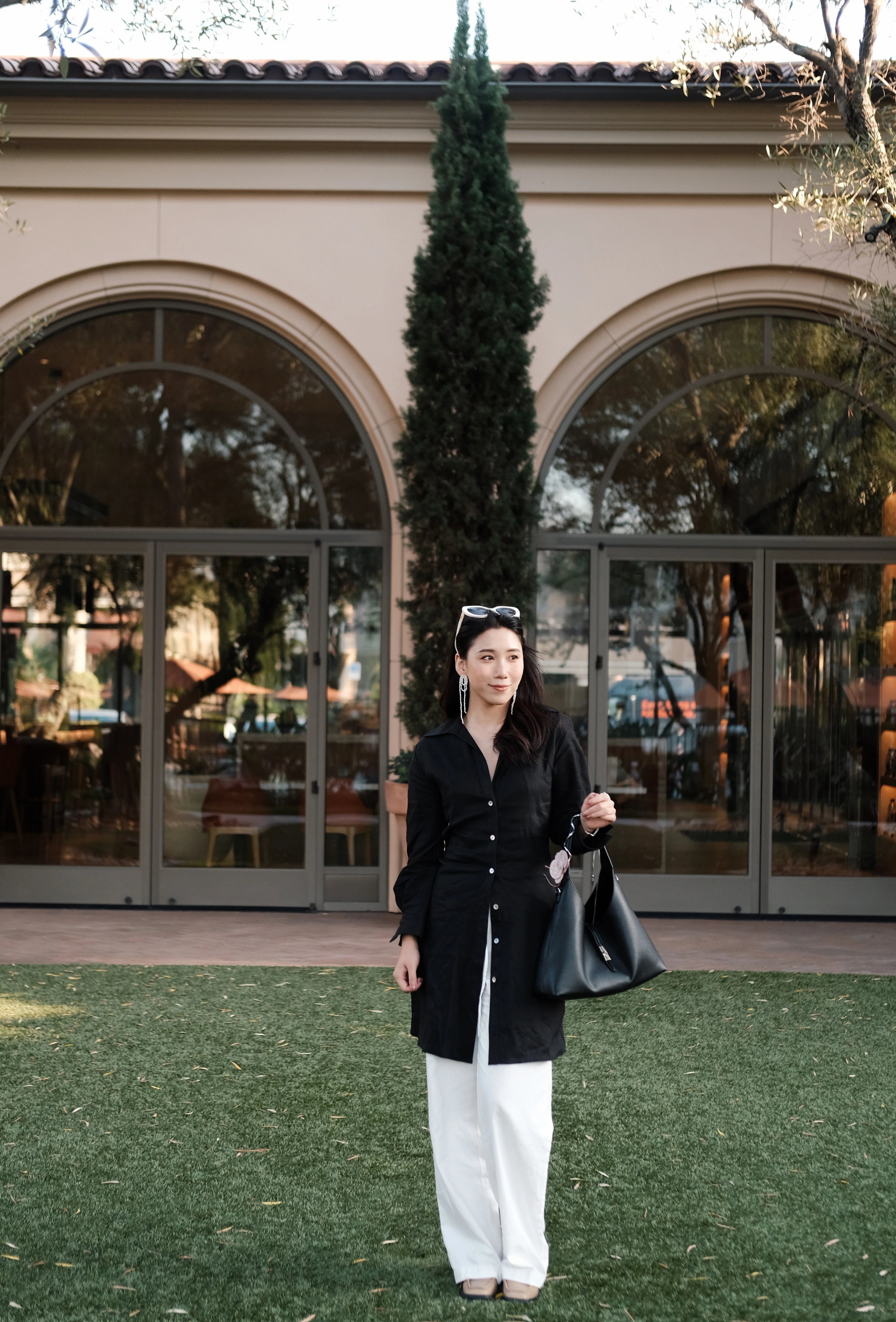 Girl holding a black tote bag standing in front of a glass door