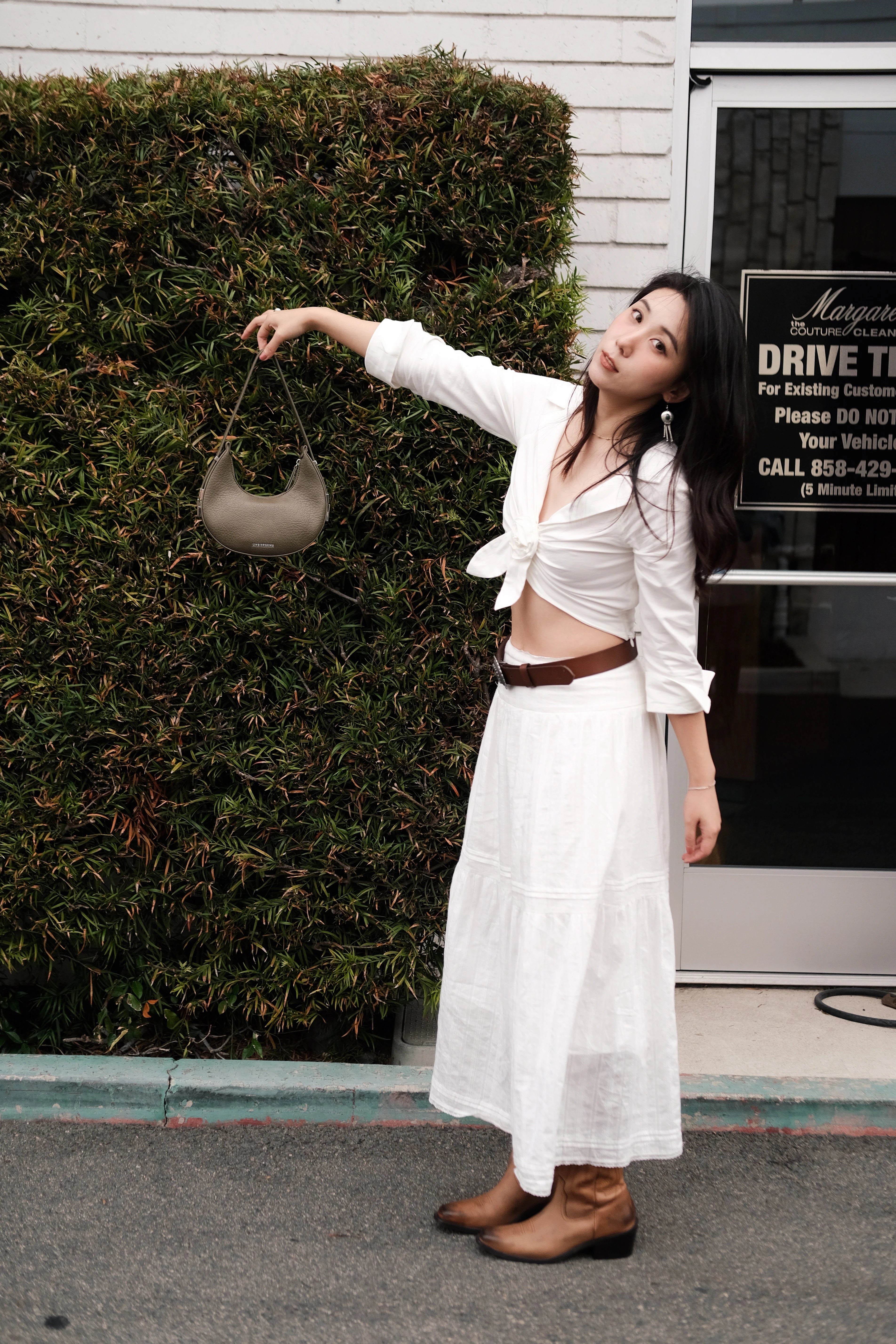 Girl wearing a white dress holding a green mini shoulder bag