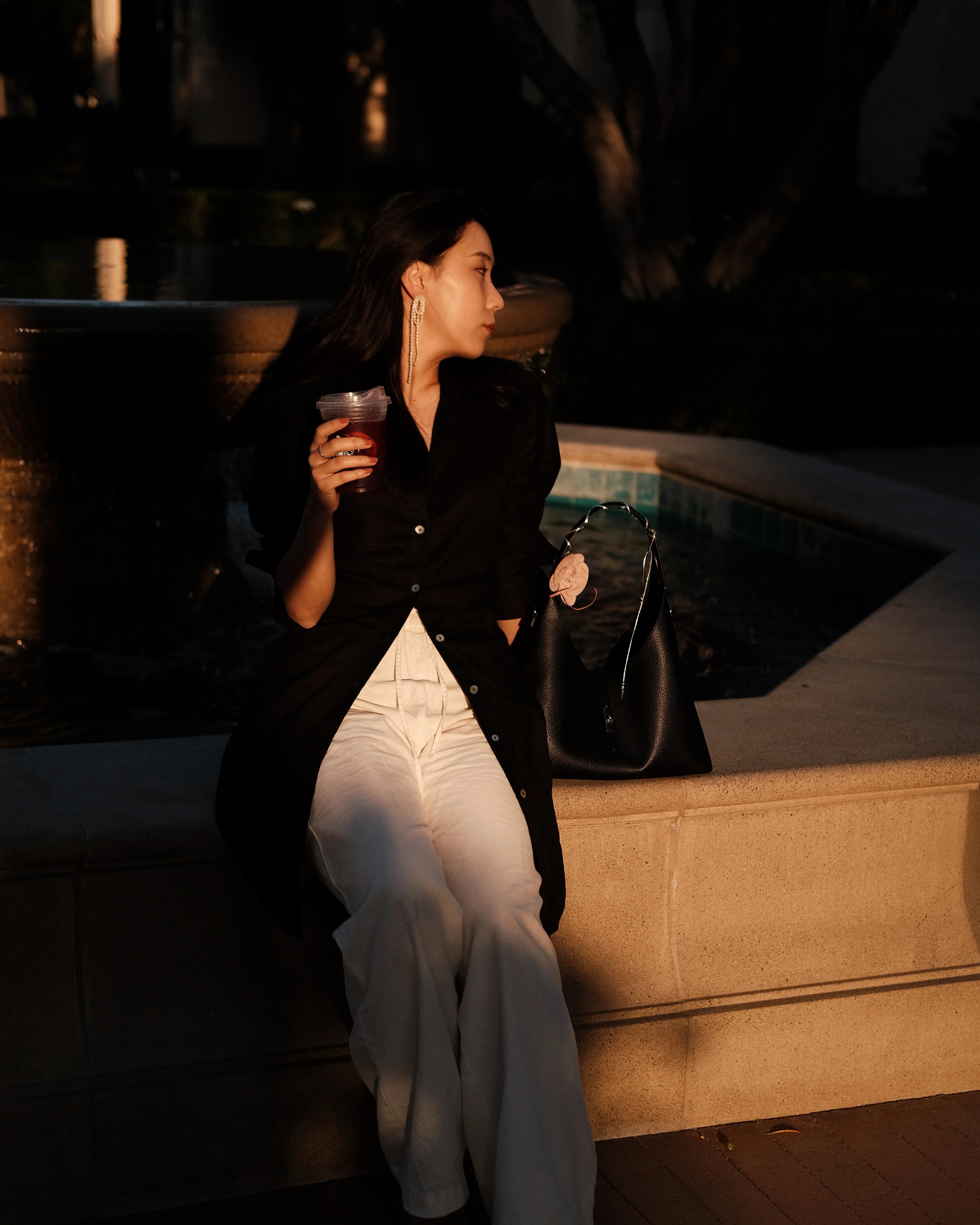 Girl holding a black tote bag standing in front of a glass door