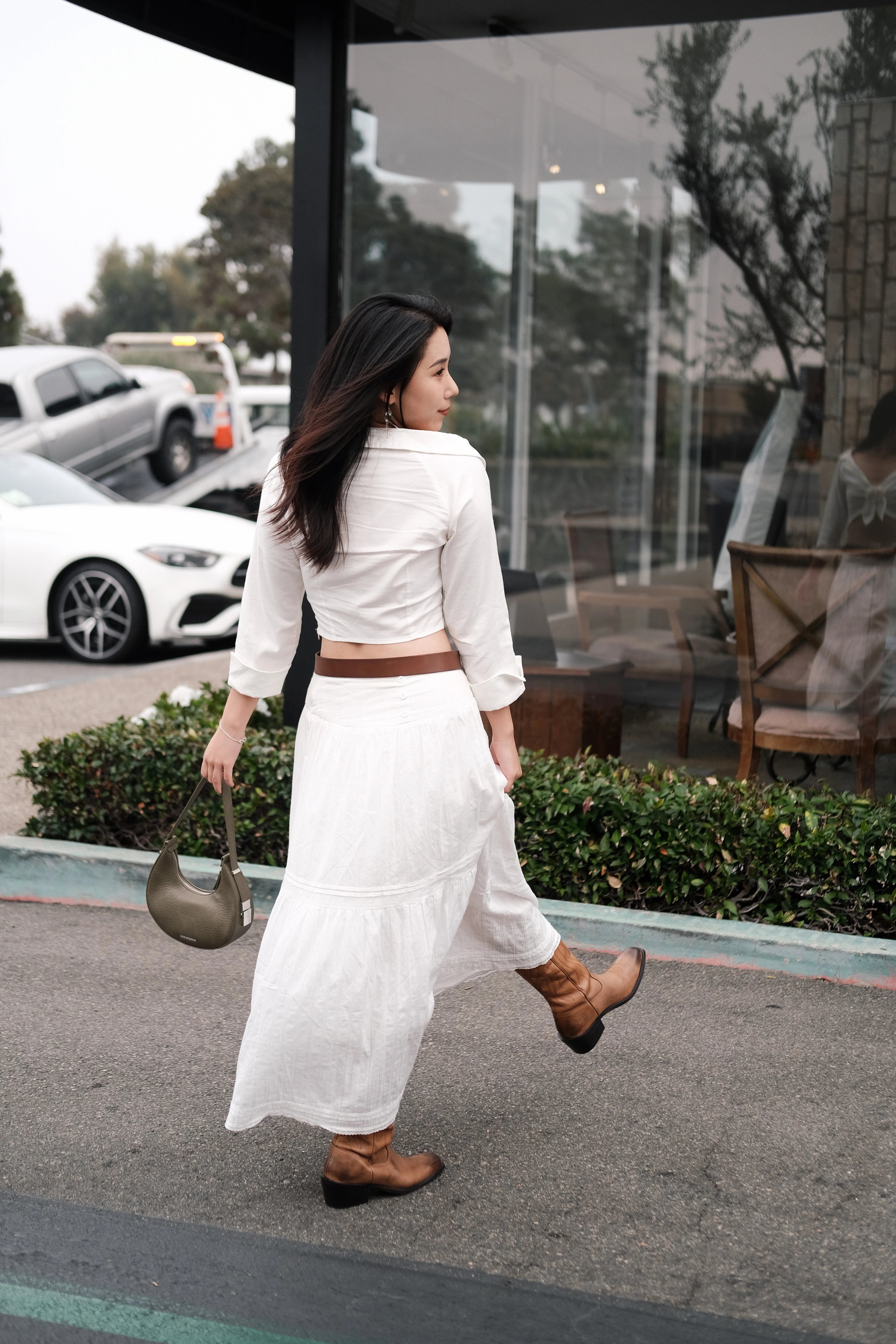 Girl wearing a white dress holding a green mini shoulder bag