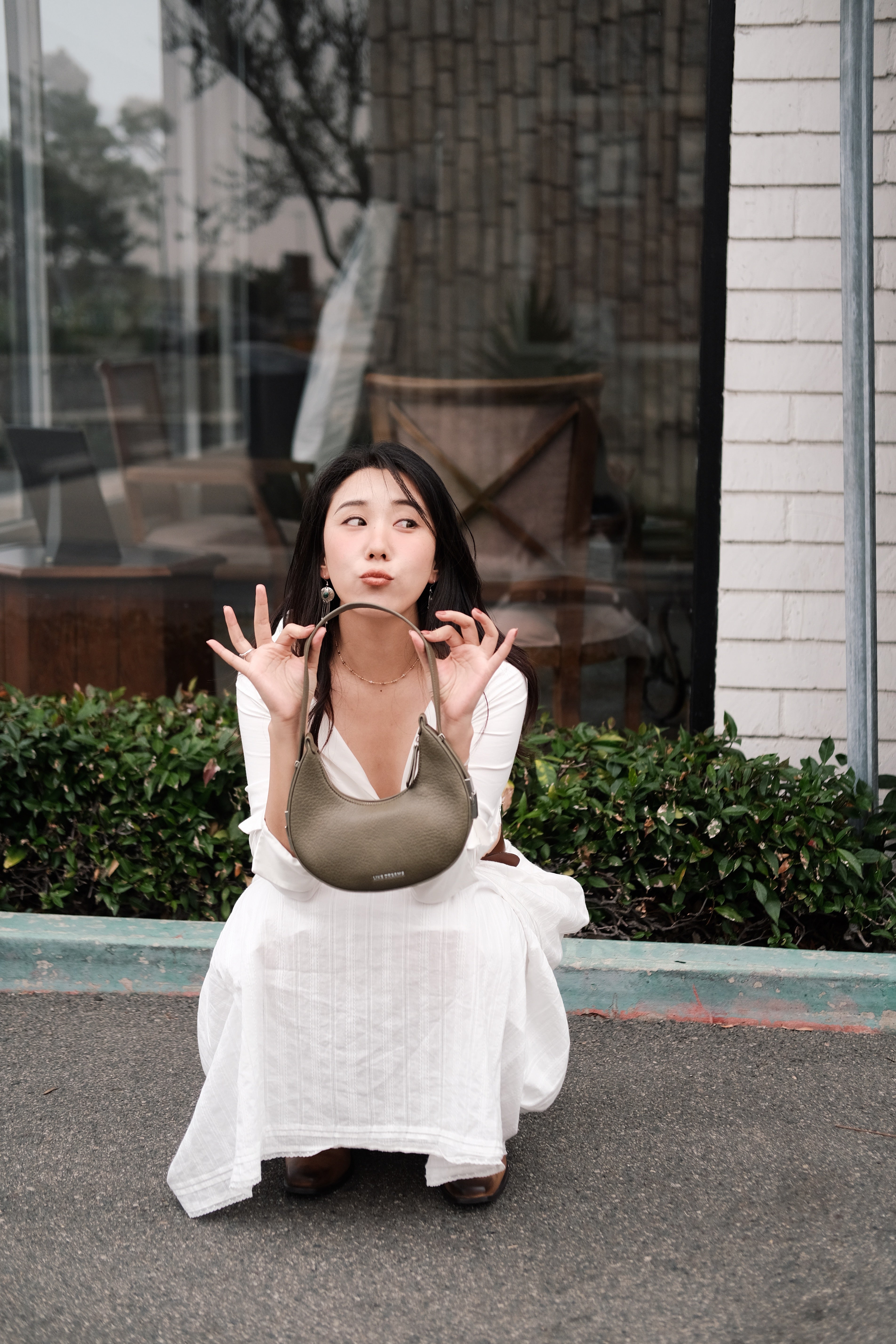 Girl wearing a white dress and holding a mini green shoulder bag