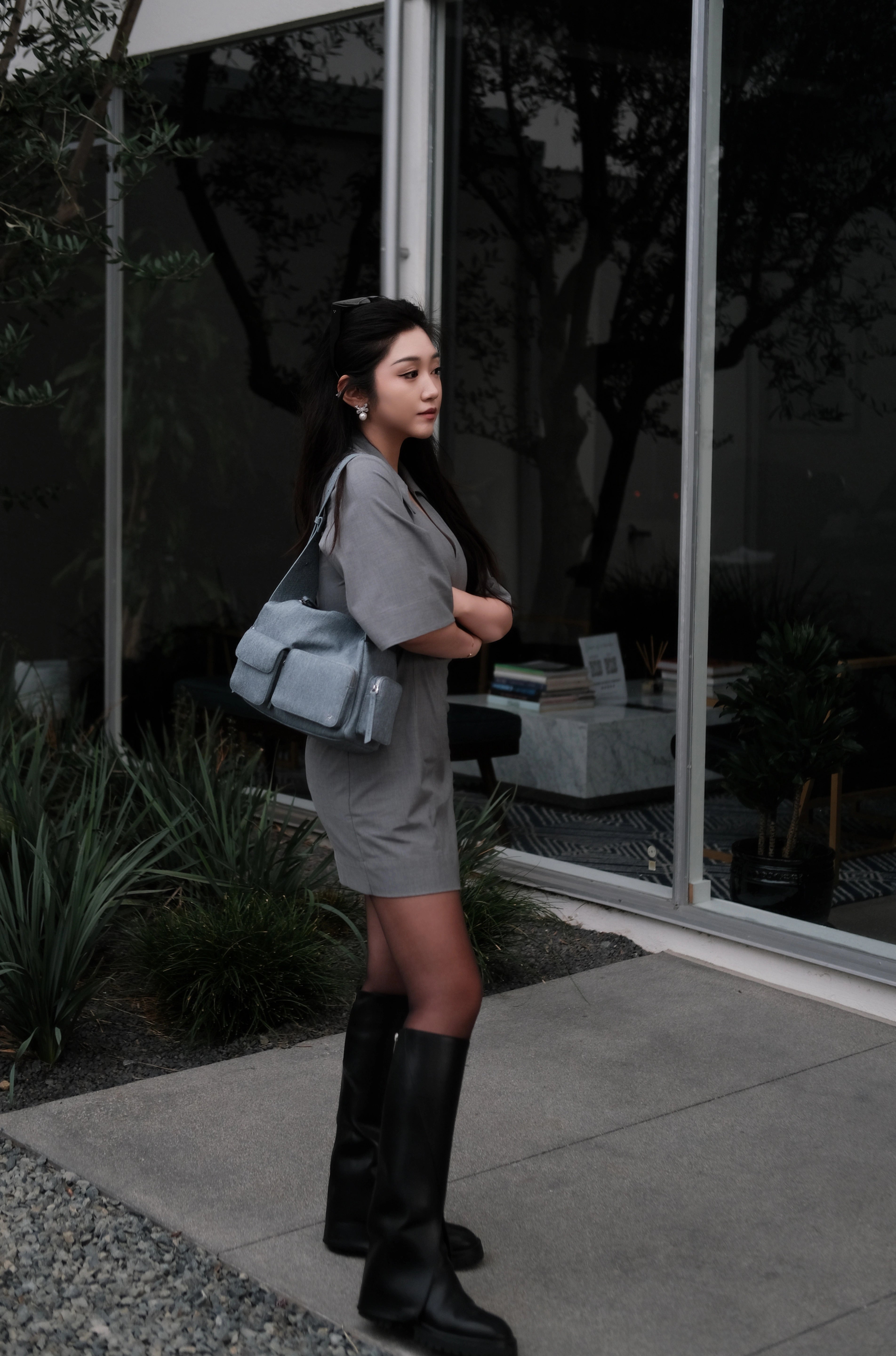 Model holding a blue large shoulder bag standing in front of a wall